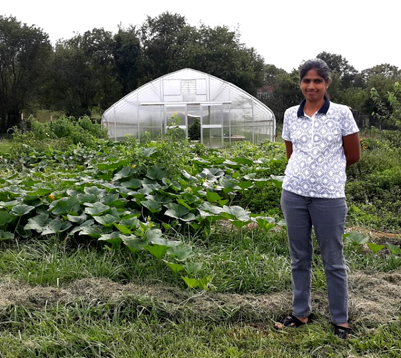 Indhu Balasubramaniam standing in front of her greenhouse.